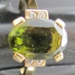 Une bague ornée d'une pierre ovale couleur olive épaulée de 4 petits diamants 