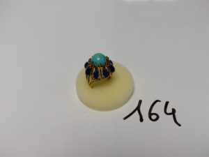 1 bague en or (modèle ancien) ornée d'une pierre centrale couleur turquoise entourée d'un rangs de petites pierres rouges (1 chaton vide) et d'un rang de pierres bleues cabochons style lapis lazuli (td52). PB 13g