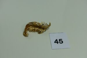 1 broche en or à décor d'une plume ornée de pierres bleues (abîmées). PB 20,1g