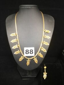 1 collier en maille parisienne, type plastron ornée de motifs filigranés et de pierres (L 42,5g) et 1 boucle d'oreille assortie. Le tout en or. PB 13,5g