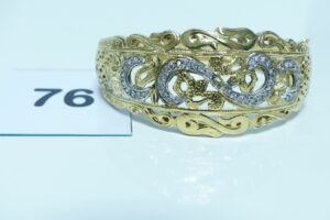 1 bracelet rigide ouvrant en or 750/1000 motif central à décor floral orné de petites pierres (2 chatons vides)(diamètr e 5,5/6,5cm). PB 15,5g