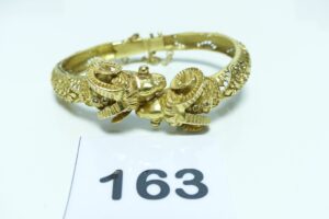1 bracelet rigide, ouvrant et ouvragé en or 750/1000 à décor de 2 têtes de bélier ornées de 4 petites pierres (chaînette de sécurié cassée,diamètre 5/6cm). PB 39,3g