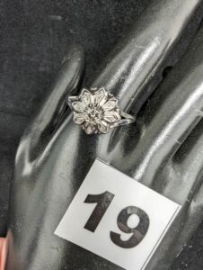 1 Bague motif fleur ornée d'un diamant (TD66) en or gris 750/1000 18k. PB 3,8g