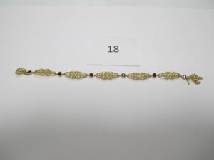 1 Bracelet en or 18k(750/1000)ouvragé etrehaussé de 6 pierres bordeaux(chainettede sécurité cassée)(L18cm).PB 11,85g.