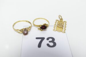 2 Bagues en or 750/1000 (1 ornée d'une petite pierre couleur grenat Td49 et 1 ornée d'une petite pierre violette T55) et 1 pendentif coran en or 750/1000. PB 4,4g