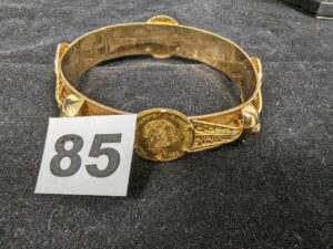 1 Bracelet rigide orné d'éléments filigranés en relief et de 4 pièces autrichienne, en or 916 et 750/1000 22k et 18k. PB 36,2g