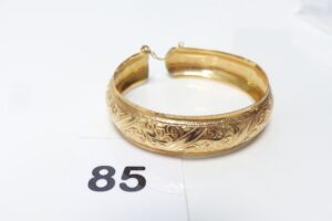 1 Bracelet rigide ouvragé et ouvert avec chaînette de sécurité, or 750/1000 18k (diamètre 6,5cm). PB 23,4g