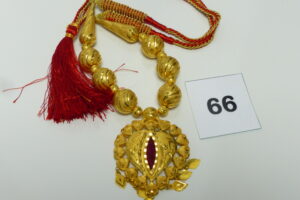 1 Collier à décor de boules ouvragées montées sur cordon en tissu, motif central orné d'une pierre rouge. Le tout en or 875/1000 21k. PB avec cordon 41,5g