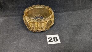 1 Bracelet rigide orné d'éléments filigranés en relief, ornés de pièces de20fr Napoléon III serties griffes 916/1000, monture (Diam 6,5cm) en or 750/1000 . PB 80,7g