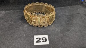 1 Bracelet rigide orné d'éléments filigranés en relief et de 4 pièces de 20fr Napoléon III tête laurée en or 916/1000 22k, serties griffes, monture (Diam 7,2cm) en or 750/1000 18k. PB 74,7g