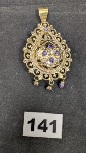 1 Pendentif Meskia orné de strass violet et blanc (L9cm, légèrement tordu), en or 750/1000 18k. PB 13,88g
