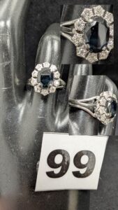 1 Bague rehaussée d'une pierre bleue emoussée dans un entourage de petits diamants (TD54) en or gris 750/1000 18k. PB 4,67g