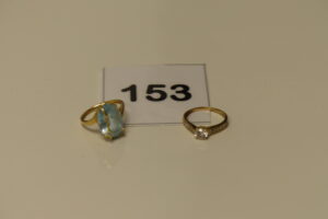 2 Bagues (1 ornée de pierres, Td48)(1 réhaussée d'une grosse pierre bleue ciel et de 2 petits diamants, Td51), le tout en or 750/1000 (18K). PB 5,8g